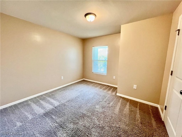 unfurnished room with dark colored carpet and baseboards