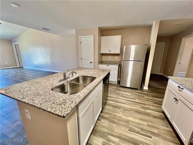 kitchen with appliances with stainless steel finishes, a sink, light wood-type flooring, white cabinets, and baseboards
