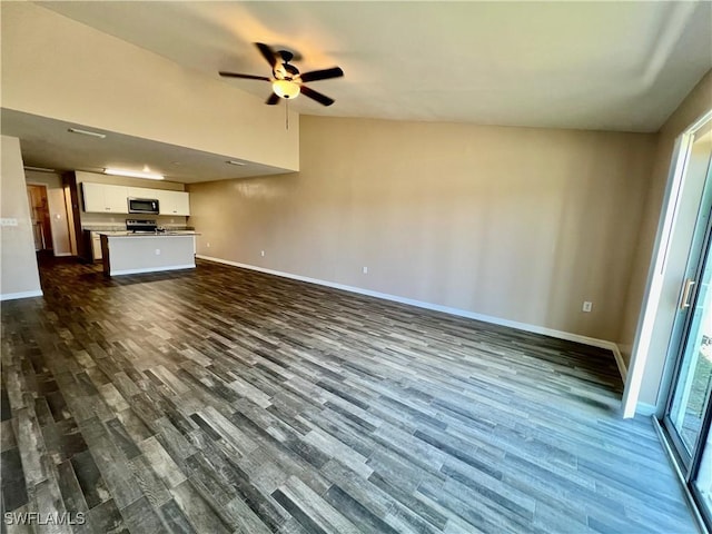 unfurnished living room with dark wood finished floors, baseboards, and a ceiling fan
