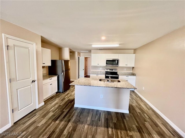 kitchen with stainless steel appliances, dark wood finished floors, white cabinets, baseboards, and an island with sink
