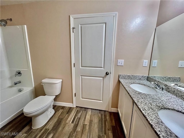 full bathroom featuring wood finished floors, toilet, double vanity, baseboards, and shower / tub combination