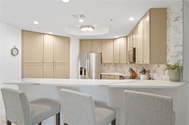 5793 Cape Harbour Dr Unit 1111, Cape Coral, FL 33914 - kitchen with appliances with stainless steel finishes, a peninsula, recessed lighting, decorative backsplash, and light stone counters