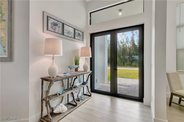 doorway featuring french doors, light wood-style flooring, and baseboards