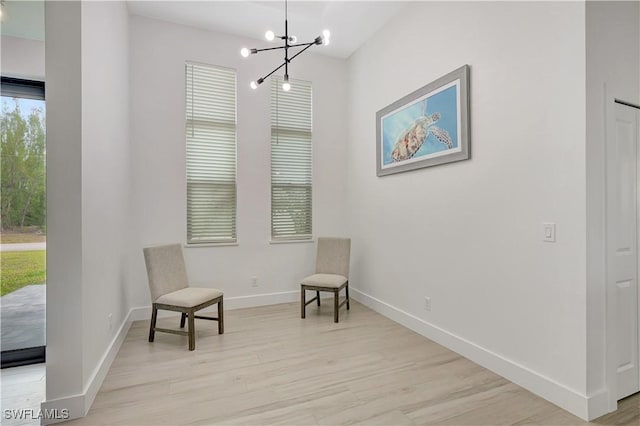 sitting room featuring light wood-type flooring, a chandelier, and baseboards
