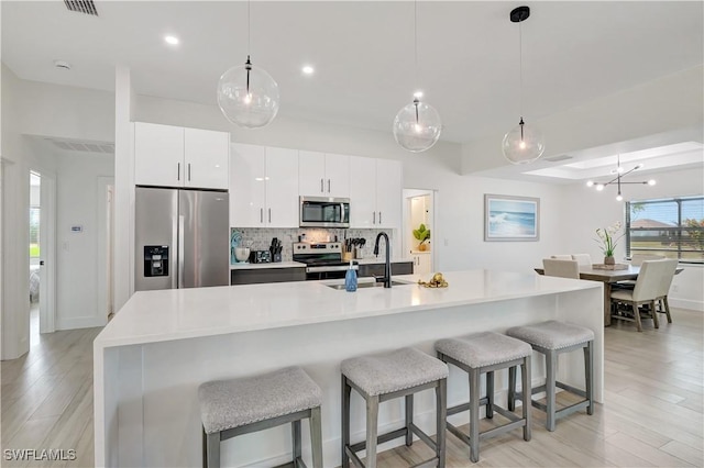kitchen featuring appliances with stainless steel finishes, light wood-style flooring, decorative backsplash, light countertops, and recessed lighting