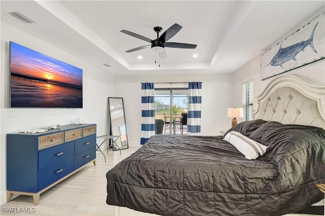 bedroom featuring access to exterior, a raised ceiling, recessed lighting, a ceiling fan, and light wood-style floors