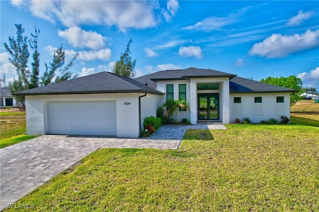 prairie-style home with french doors, a garage, stucco siding, a front yard, and decorative driveway