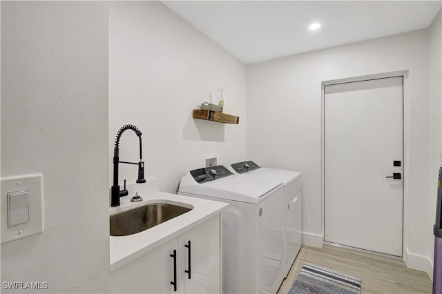 laundry area featuring washing machine and clothes dryer, light wood-style flooring, recessed lighting, cabinet space, and baseboards