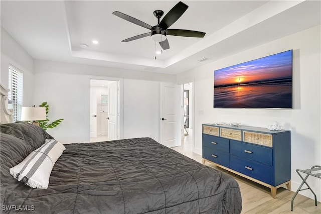 bedroom featuring a raised ceiling, light wood-style floors, ceiling fan, recessed lighting, and baseboards