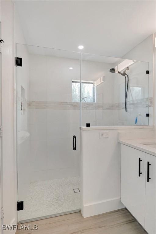 full bath with wood finished floors, a shower stall, vanity, and baseboards