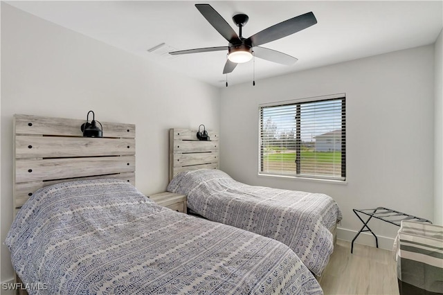 bedroom featuring wood finished floors, a ceiling fan, and baseboards
