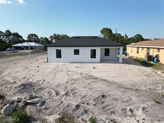 2619 15th St SW, Lehigh Acres, FL 33976 - back of property with dirt driveway and stucco siding