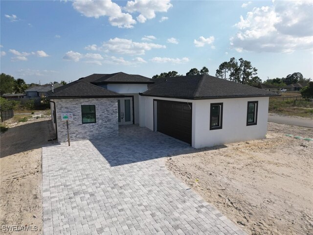 2619 15th St SW, Lehigh Acres, FL 33976 - prairie-style home featuring an attached garage, stucco siding, and decorative driveway