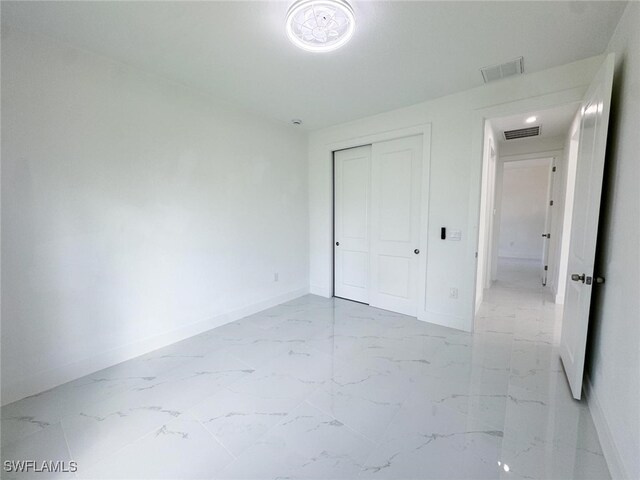 2619 15th St SW, Lehigh Acres, FL 33976 - unfurnished bedroom with baseboards, a closet, marble finish floor, and visible vents