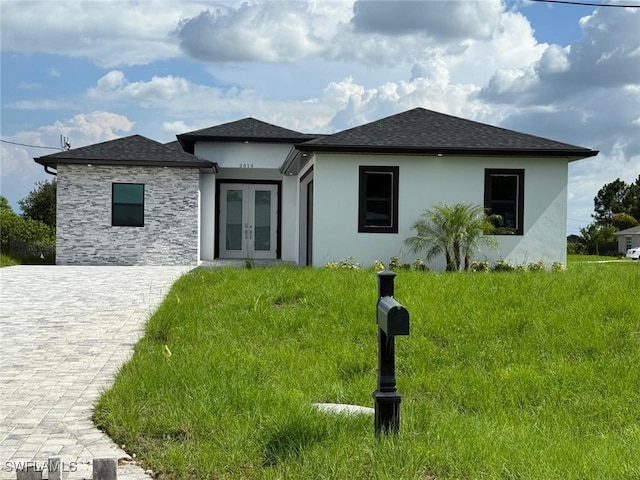 2619 15th St SW, Lehigh Acres, FL 33976 - view of front facade with french doors, stucco siding, roof with shingles, and stone siding