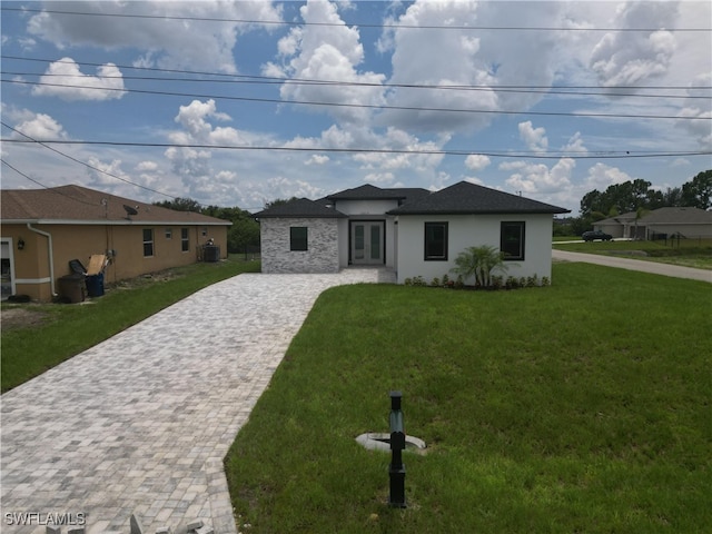 2619 15th St SW, Lehigh Acres, FL 33976 - prairie-style home with decorative driveway, stucco siding, a front lawn, and french doors