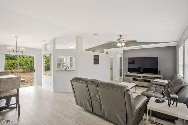 living room featuring a chandelier, a ceiling fan, light wood-style floors, baseboards, and vaulted ceiling