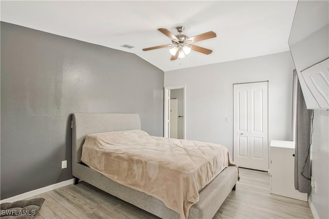 bedroom with light wood-type flooring, vaulted ceiling, baseboards, and ceiling fan