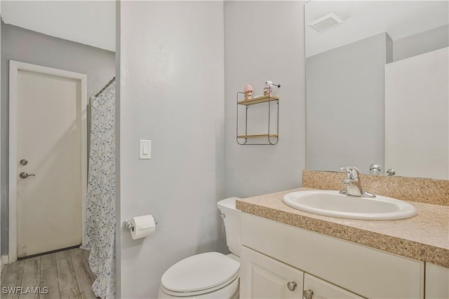 bathroom with toilet, wood finished floors, vanity, and curtained shower