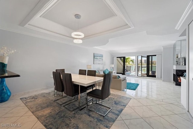 dining area featuring a warm lit fireplace and a raised ceiling