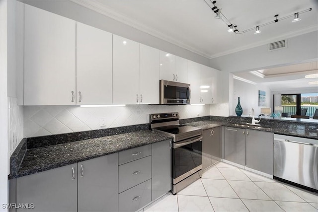 kitchen featuring a sink, ornamental molding, stainless steel appliances, and dark stone countertops