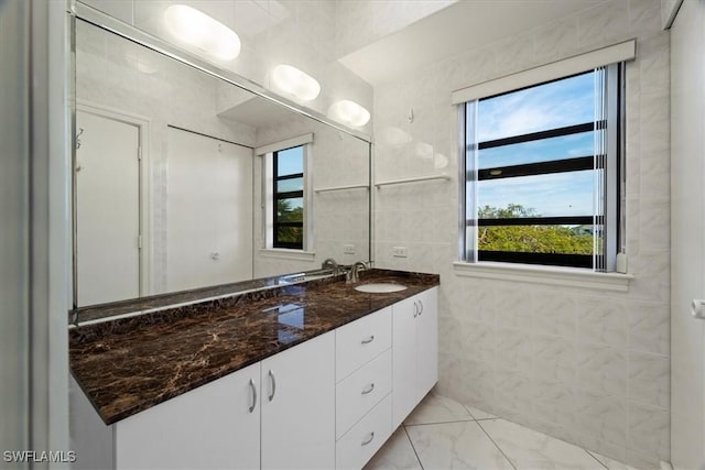 bathroom with vanity, marble finish floor, and tile walls