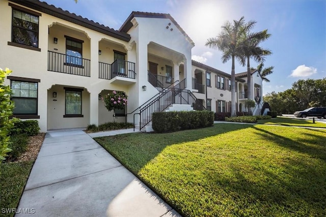 15102 Palmer Lake Cir Unit 201, Naples, FL 34109 - view of front of property with stucco siding, a front lawn, stairs, and a tiled roof