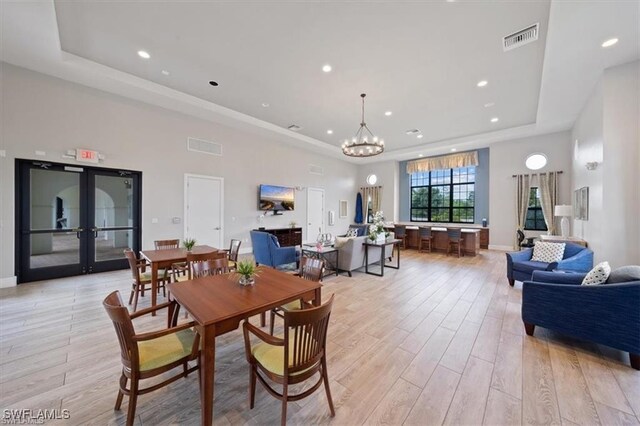 15102 Palmer Lake Cir Unit 201, Naples, FL 34109 - dining space with a tray ceiling, light wood-style flooring, french doors, recessed lighting, and a chandelier