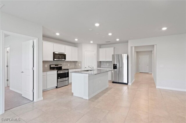 16044 Enclaves Cove Dr, North Fort Myers, FL 33917 - kitchen featuring appliances with stainless steel finishes, a sink, an island with sink, white cabinetry, and decorative backsplash