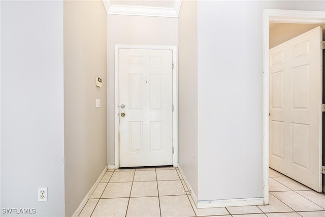 doorway to outside featuring crown molding, light tile patterned floors, and baseboards