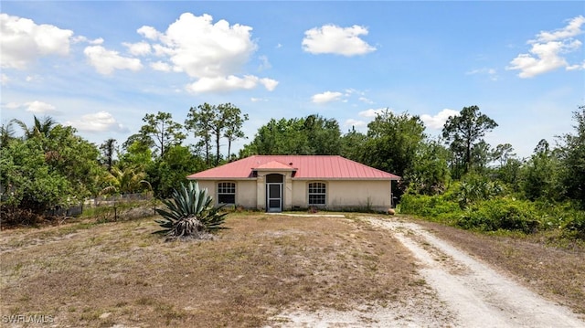 view of front of property with stucco siding, driveway, and metal roof