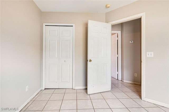 unfurnished bedroom with a closet, baseboards, and light tile patterned floors
