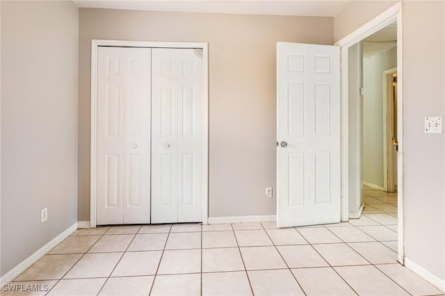 unfurnished bedroom with a closet, baseboards, and light tile patterned floors