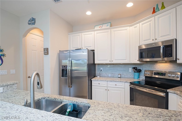 kitchen featuring backsplash, stainless steel appliances, white cabinetry, and a sink