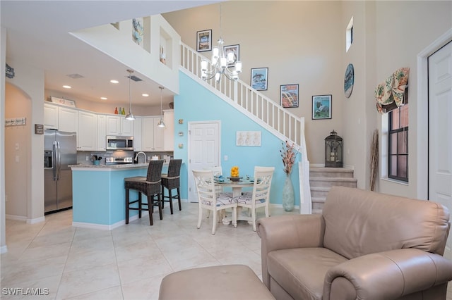 living room featuring an inviting chandelier, baseboards, light tile patterned floors, a towering ceiling, and stairway