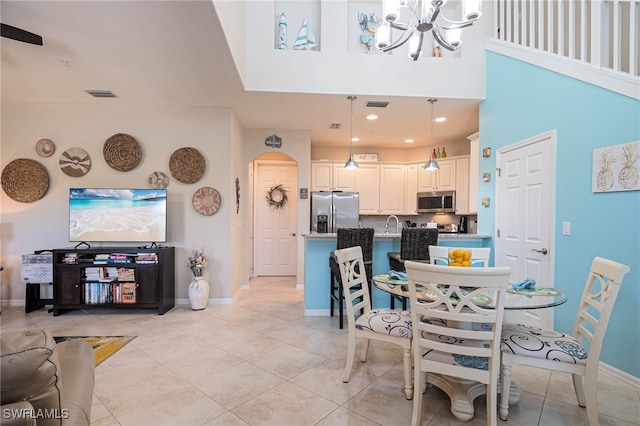 dining room with visible vents, light tile patterned floors, baseboards, a notable chandelier, and a high ceiling