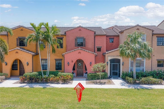 mediterranean / spanish-style home featuring french doors, stucco siding, a tiled roof, and a front yard