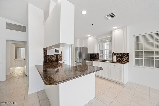 4788 San Carlo Ct, Naples, FL 34109 - kitchen with stainless steel appliances, a peninsula, light tile patterned floors, decorative backsplash, and white cabinetry