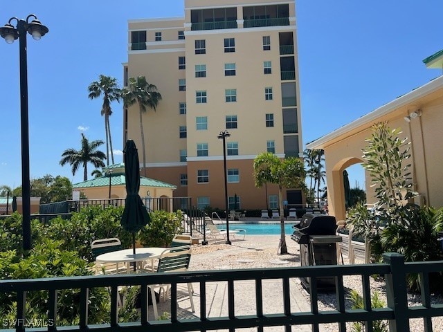 pool featuring a patio area, fence, and grilling area