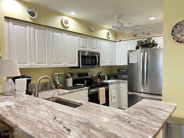kitchen featuring light stone countertops, recessed lighting, white cabinets, a sink, and stainless steel appliances