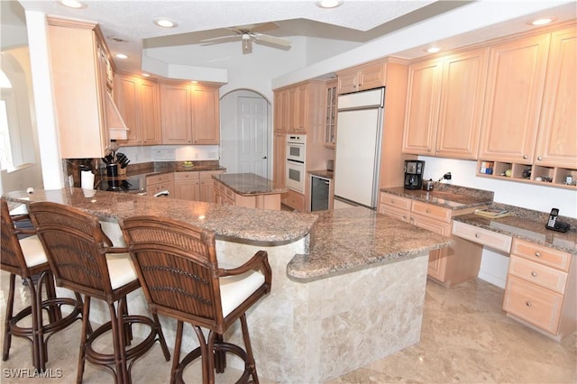 3787 Whippoorwill Ct, Punta Gorda, FL 33950 - kitchen featuring arched walkways, built in refrigerator, a peninsula, and light brown cabinetry