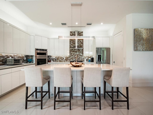 kitchen with backsplash, appliances with stainless steel finishes, modern cabinets, and a kitchen bar