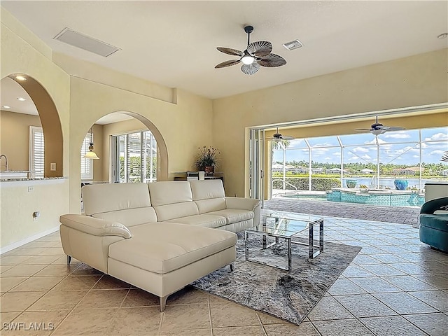 20710 Mystic Way N, Fort Myers, FL 33917 - living area featuring ceiling fan, a sunroom, light tile patterned floors, arched walkways, and baseboards