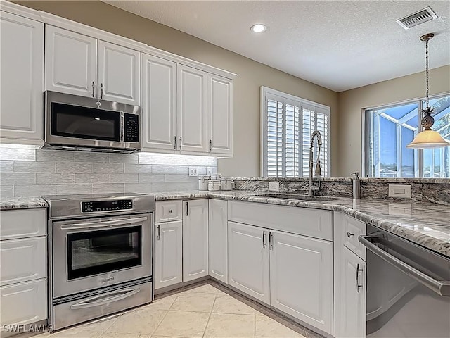 20710 Mystic Way N, Fort Myers, FL 33917 - kitchen with appliances with stainless steel finishes, a sink, white cabinetry, hanging light fixtures, and light stone countertops