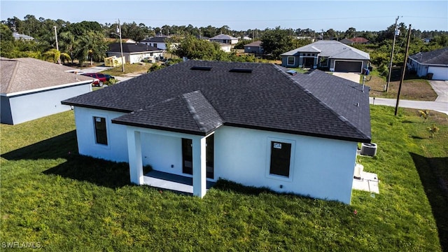 3610 22nd St SW, Lehigh Acres, FL 33976 - back of house featuring a shingled roof, central AC, a yard, and a residential view
