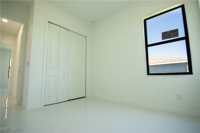 3610 22nd St SW, Lehigh Acres, FL 33976 - unfurnished bedroom featuring a closet, baseboards, and tile patterned floors