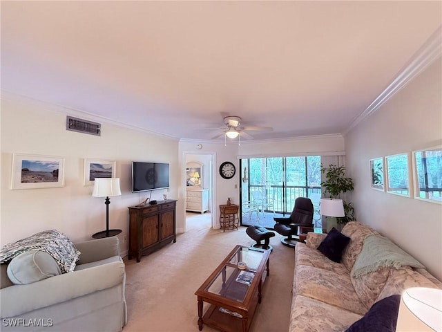 living area with light colored carpet, a ceiling fan, visible vents, and ornamental molding