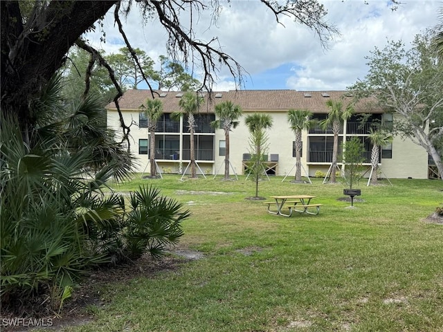 back of property featuring a lawn and stucco siding