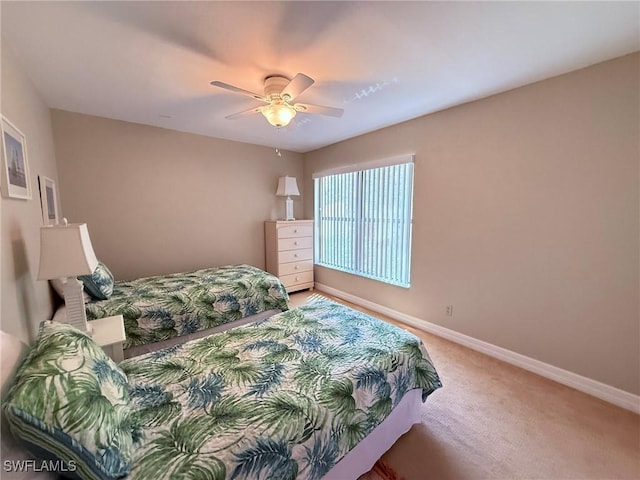 bedroom featuring light colored carpet, a ceiling fan, and baseboards
