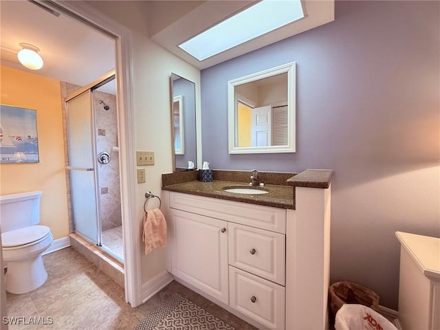 bathroom featuring vanity, a skylight, toilet, and a shower stall